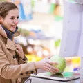 Young woman weighing produce in a grocery store checkout