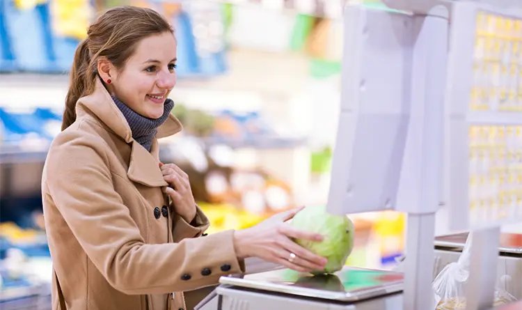 Young woman weighing produce in a grocery store checkout