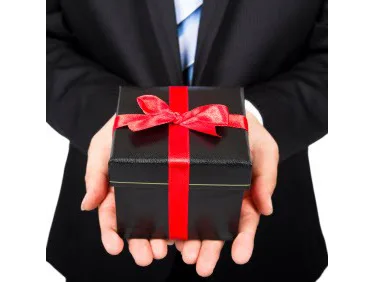 Businessman in a dark suit holding a dark gift box with a bright red bow and ribbon
