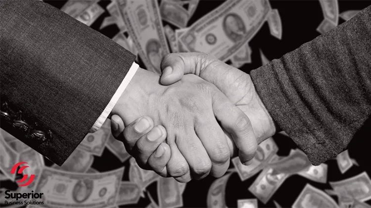 Cliché business handshake with money falling in the background.